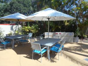 邦加里普莱西德沃特斯假日公寓的庭院里配有两张桌子和椅子以及遮阳伞