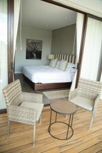 卢萨卡Le Elementos Boutique Hotel的一间卧室配有一张床、两把椅子和一张桌子