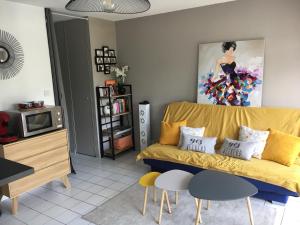 基伯龙Appartement T2 refait à neuf, piscine的客厅配有黄色沙发和绘画作品
