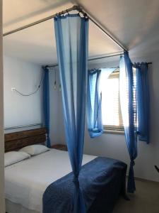格罗塞托港il Mandriolo的一间卧室配有一张带蓝色窗帘的床和一扇窗户