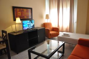 塞维利亚卢克瑟维亚宫公寓的客厅配有电视、沙发和桌子
