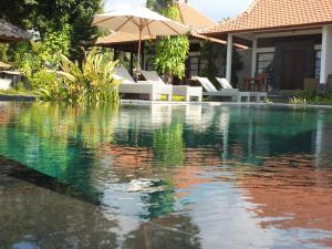 特贾库拉阿姆瑞塔盐田别墅旅馆的一个带椅子和遮阳伞的游泳池