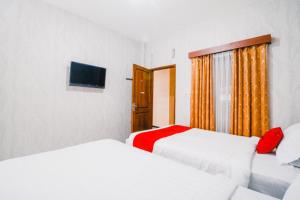 玛琅RedDoorz near Taman Rekreasi Selecta的一间卧室配有两张床和电视。