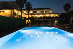 卡塔尼亚乐度纳西西里酒店的大楼前的大型蓝色游泳池