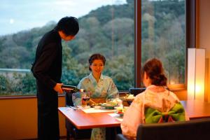 琴平町琴平町樱花之所大酒店的坐在餐桌旁吃食物的男人和女人