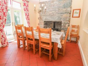 达夫林Tyddyn Goronwy的一间带桌椅和石制壁炉的用餐室