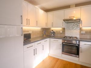 圣梅尔林11 Pendarves的厨房配有白色橱柜和不锈钢用具