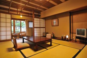 山之内町Shibu Onsen KOKUYA的客厅配有木桌和电视。