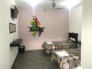图斯特拉古铁雷斯HOTEL LOS PINOS CENTRO的一间设有两张床的客房,墙上有一只鹦鹉