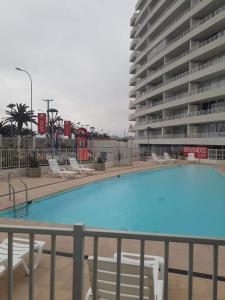 拉塞雷纳Departamentos La Serena Vista的一座带椅子的游泳池以及一座大型建筑