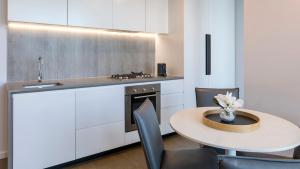 墨尔本Avani Melbourne Central Residences的厨房配有桌子、水槽和炉灶。