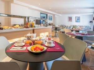 阿雅克修阿雅克修美居酒店的用餐室配有餐桌和食物