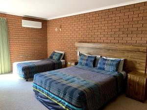 托克姆沃尔Kingswood Motel的一间卧室设有两张床和砖墙