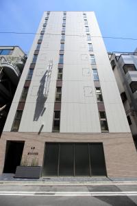 东京HOTEL AMANEK Ginza East的一座高大的建筑,上面有一个人的雕像