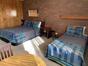托克姆沃尔Kingswood Motel的一间设有两张床和一张桌子的房间
