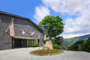 箱根THE HIRAMATSU HOTELS & RESORTS SENGOKUHARA HAKONE的前面有旗帜和岩石的建筑