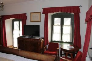 帕波艾迪福马鲁姆佛家度巴洛克尤德瓦达旅馆的一间卧室配有床、电视和红色窗帘