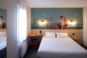 拉沙佩勒圣梅曼KYRIAD DIRECT Orleans - La Chapelle St Mesmin的酒店客房设有一张床,墙上挂有绘画作品