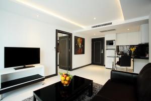 芭堤雅市中心Nova Suites Pattaya by Compass Hospitality的客厅配有电视、沙发和桌子