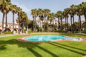 开普敦岛屿俱乐部酒店及公寓的一座楼前种有棕榈树的游泳池