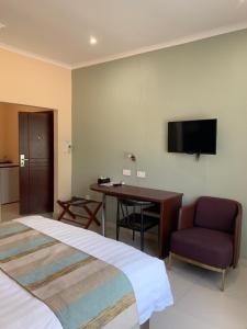 哈博罗内Bannerloft Guest house的酒店客房配有一张床、一张书桌和一台电视。