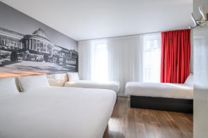 布鲁塞尔B&B HOTEL Brussels Centre Gare du Midi的一间设有三张床和红色窗帘的房间