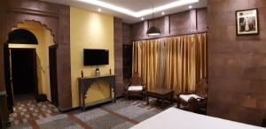 焦特布尔Jodhpur Palace Guest House的客厅配有电视、沙发和椅子