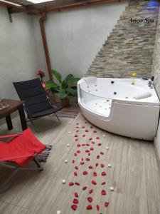 UcedaCasas Toya Jacuzzi的浴缸位于铺有红色玫瑰花瓣的木地板上
