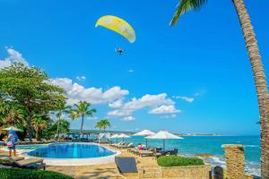 喀巴里特维林罗海滩公寓式度假酒店的风筝在海边游泳池上飞行的人