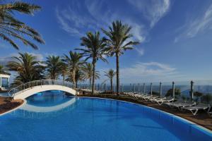 丰沙尔Pestana Grand Ocean Resort Hotel的一座带桥梁和棕榈树的游泳池