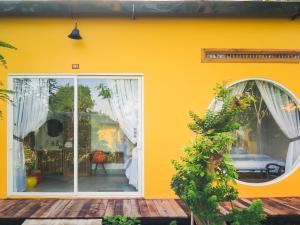 芹苴Binh Minh Eco Lodge的黄色的房屋,配有白色的窗帘和庭院
