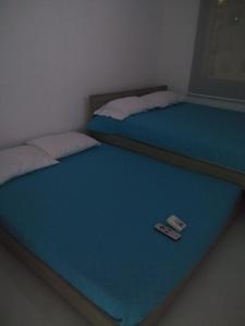 吉拉尔多特Acogedor apartamento en Girardot, fresco y tranquilo的床上遥控器的客房内的两张床