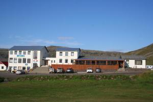 BreiðavíkHotel Breidavik的白色的建筑,有汽车停在停车场