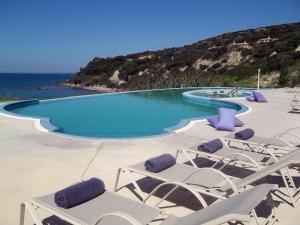 斯卡费迪亚爱奥尼亚马雷代套房度假酒店的一个带躺椅的游泳池和海洋