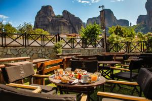 卡兰巴卡Tsikeli Boutique Hotel Meteora - Adults Friendly的餐厅配有桌椅,位于山脉的背景中