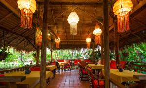 山甘烹清迈秘密花园酒店的餐厅设有桌椅和吊灯。