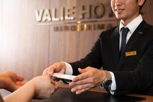 广岛Valie Hotel Hiroshima的一个人把遥控器交给一个人