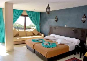 阿加迪尔蒂里拉套房酒店的一间卧室配有一张大床和一张沙发