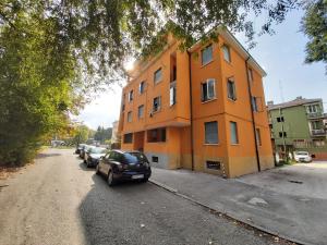 马格拉Appartamento Venezia的一座橙色的建筑,前面有汽车停放