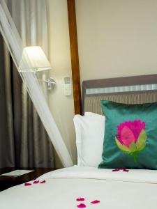 布兰太尔赛伦迪布套房和会议中心酒店的一张带绿色枕头的床,上面有粉红色的花