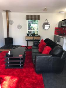 阿卡罗阿Hideaway - A Couples Retreat的客厅配有黑色皮沙发和红色地毯