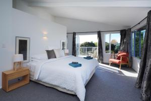 SurfdaleWaiheke Island Vineyard Holiday Houses的白色卧室配有一张大床和椅子