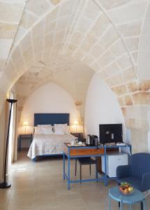 托雷圣苏桑纳Antica Masseria Torre Mozza的一间卧室配有一张床和一张书桌及电视
