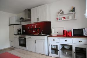 SulzfeldFerienwohnung Memmel的厨房配有白色橱柜和红色家电