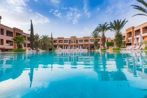 马拉喀什扎拉城温泉酒店的棕榈树和建筑度假村内的游泳池