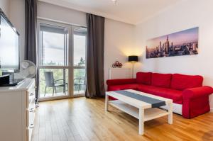 华沙Galeria Rondo Wiatraczna Apartments的客厅配有红色的沙发和桌子