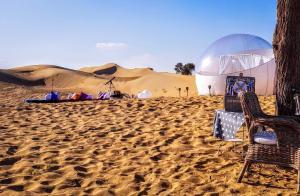 迪拜STARLIGHT CAMP的沙漠,沙滩上摆放着两把椅子和一顶帐篷