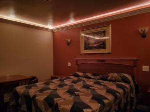 唐尼Deluxe Motel, Los Angeles Area的卧室配有一张床,墙上挂有绘画作品