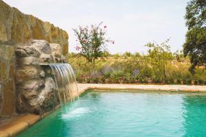 奥尔塔-德圣胡安Casa rural Mas del Serranet的石墙内一个带瀑布的游泳池