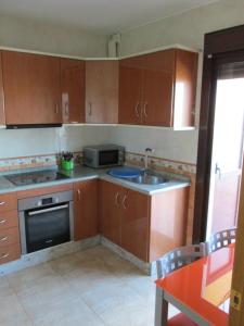 卡索拉alojamiento fernando的厨房配有木制橱柜、水槽和炉灶。